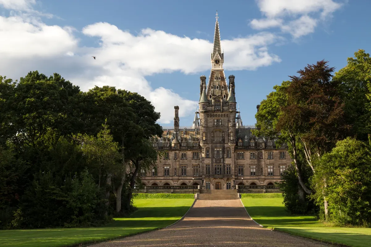 The central tower of Fettes College beyond a tree-lined drive and lawns